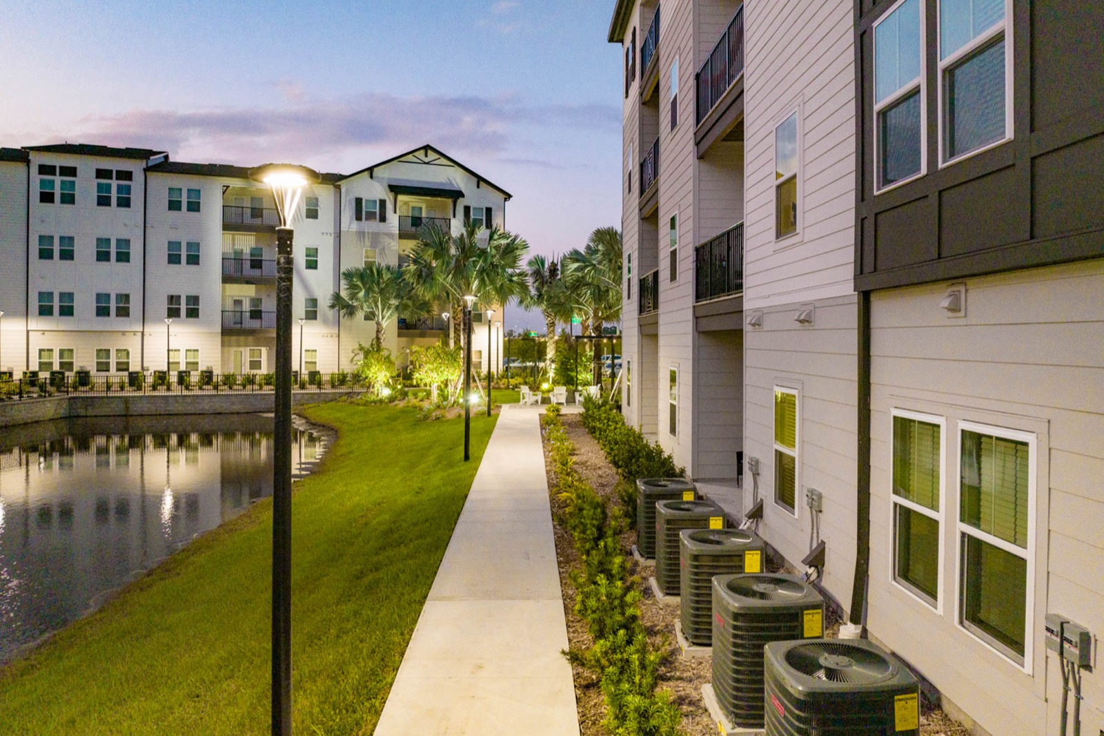 Building elevations along the pond walkway at The Avery at dusk